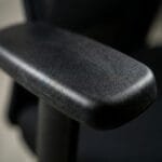 Close-up view of a black ergonomic office chair armrest designed for comfortable arm support during long working hours.